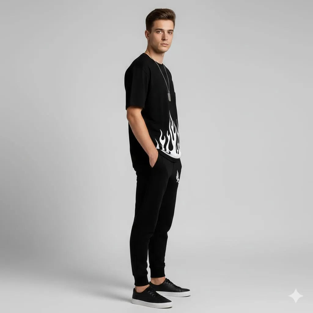 Man wearing a black t-shirt with white flame design and black pants on a gray background