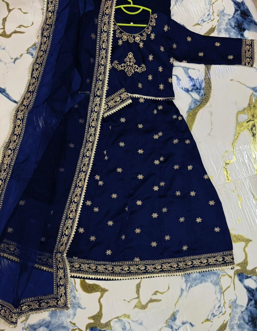 Blue embroidered traditional outfit on a floral-patterned fabric background