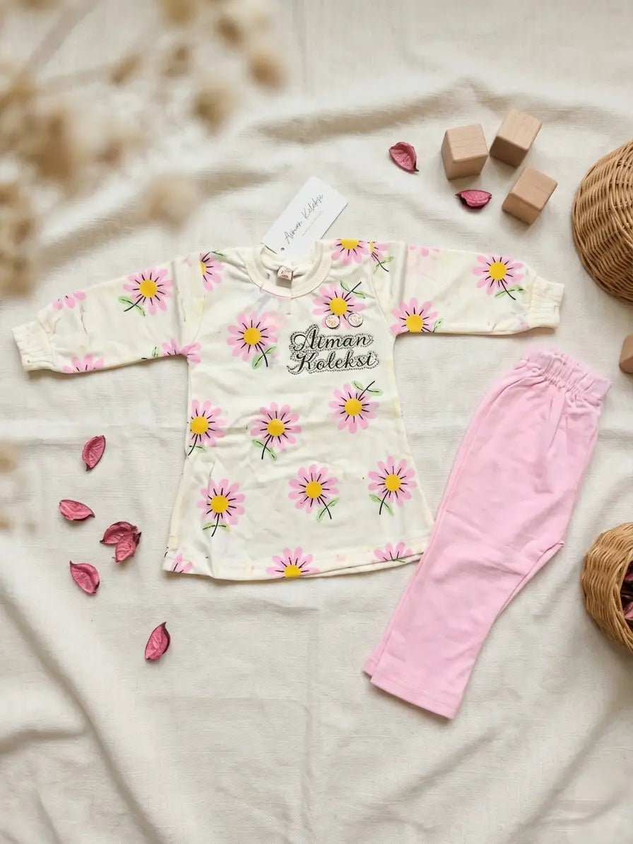 Children's outfit with floral pattern and pink pants on a soft surface.